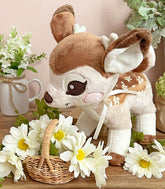 Cinnafawn Deer Plush looking down at a wicker basket of white flowers